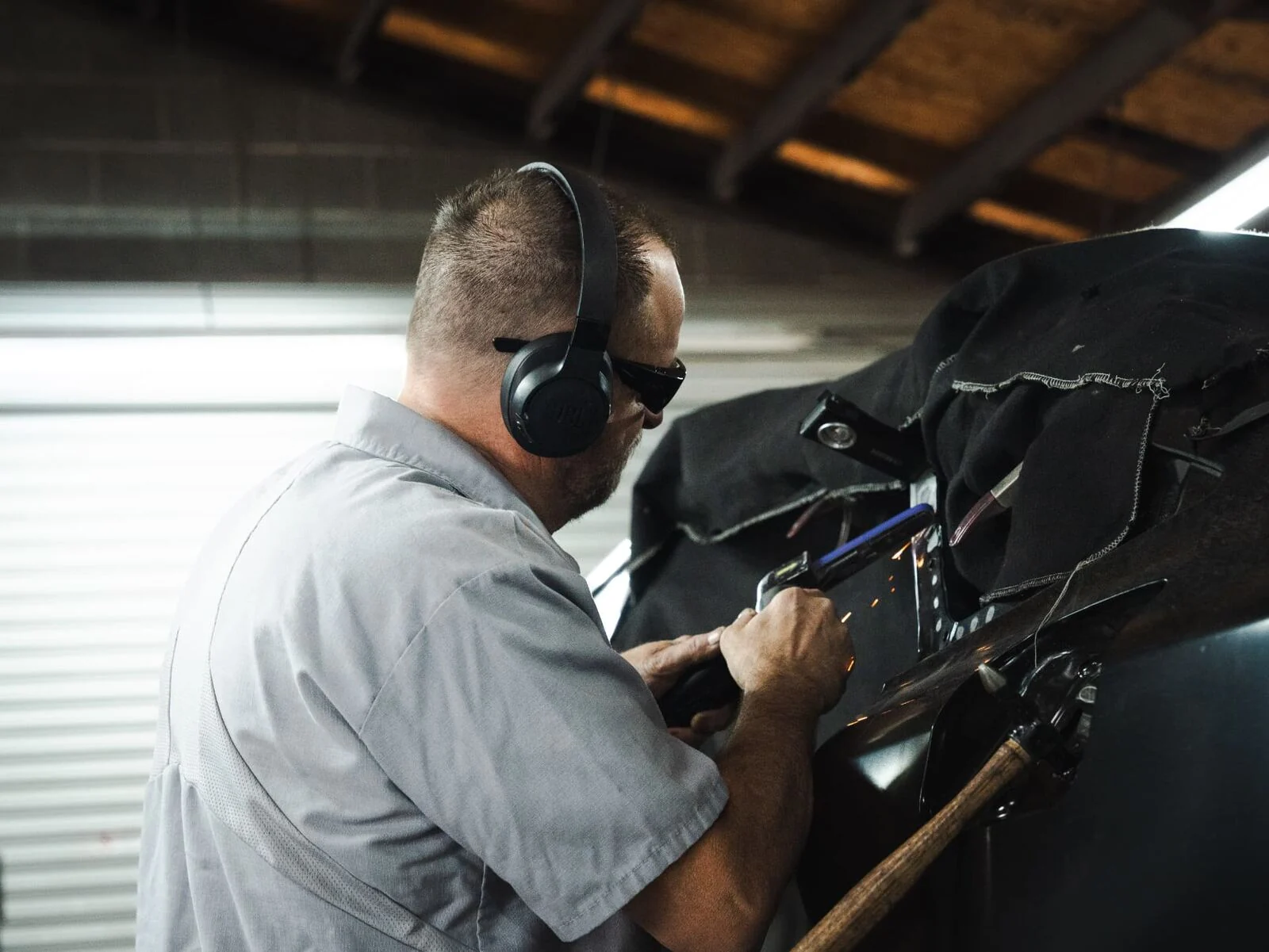 Body technician grinding a structural panel during collision repair