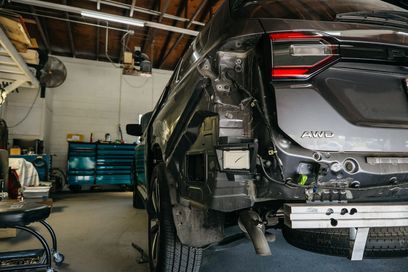 Rear collision damage disassembled for repair on a grey SUV in the repair bay