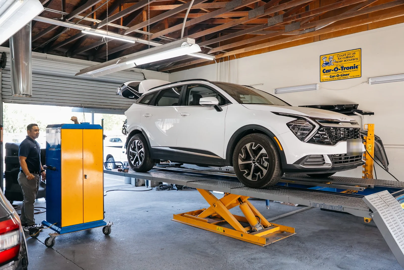 White SUV raised on the Car-O-Liner frame bench rack inside the Renewal Body Works repair bay in Clovis