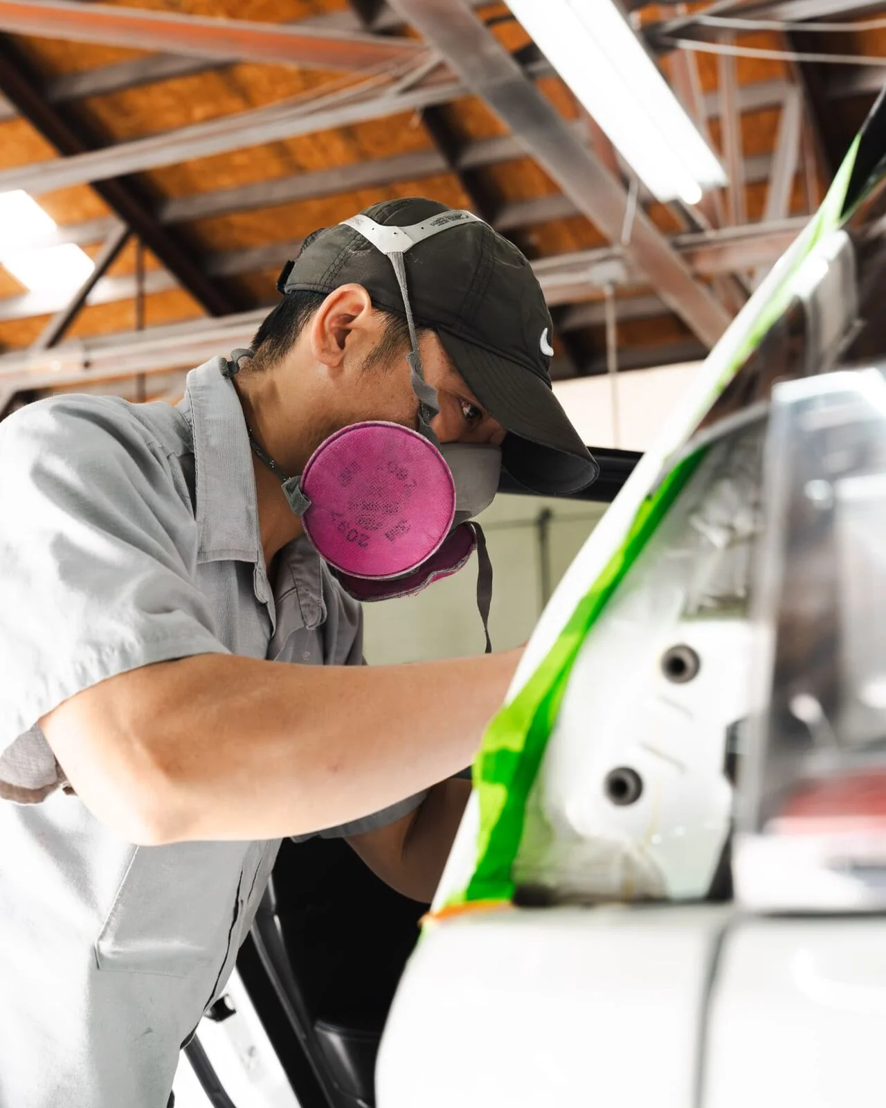 Paint technician in a respirator checking masking before spraying