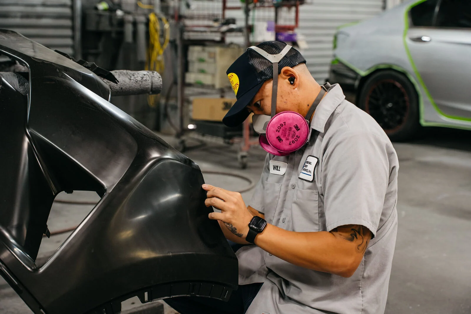 Technician sanding a bumper cover in preparation for refinishing