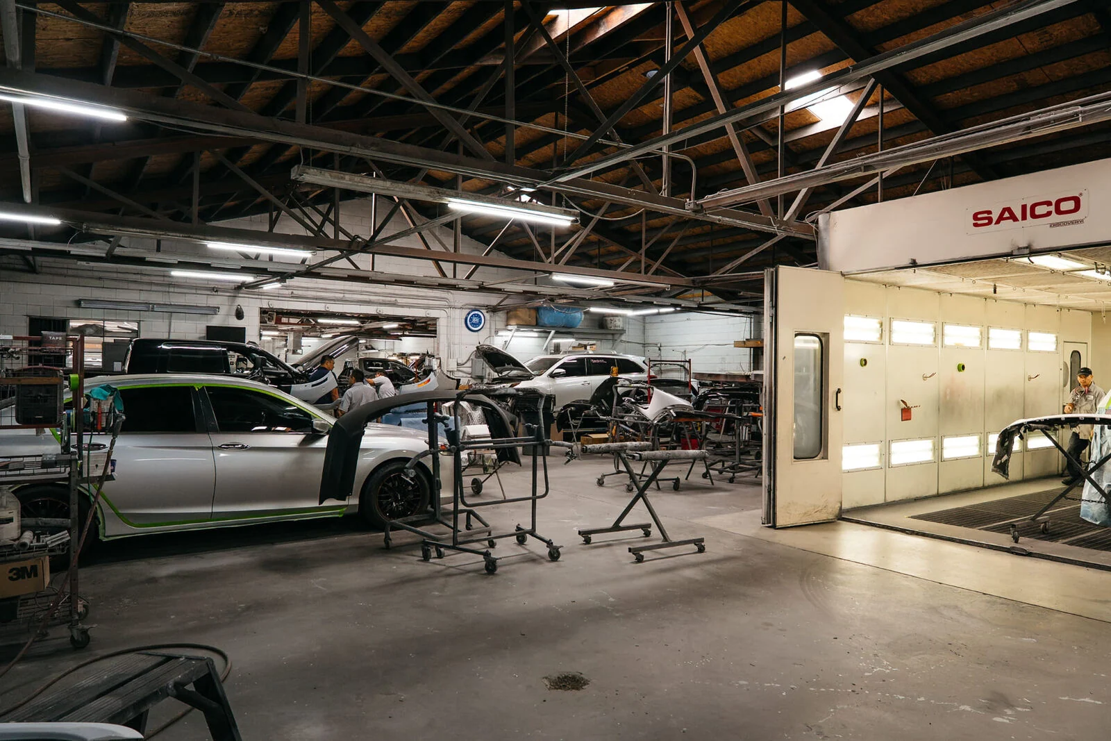 Interior of the Renewal Body Works shop in Clovis with vehicles in progress beside the paint booth